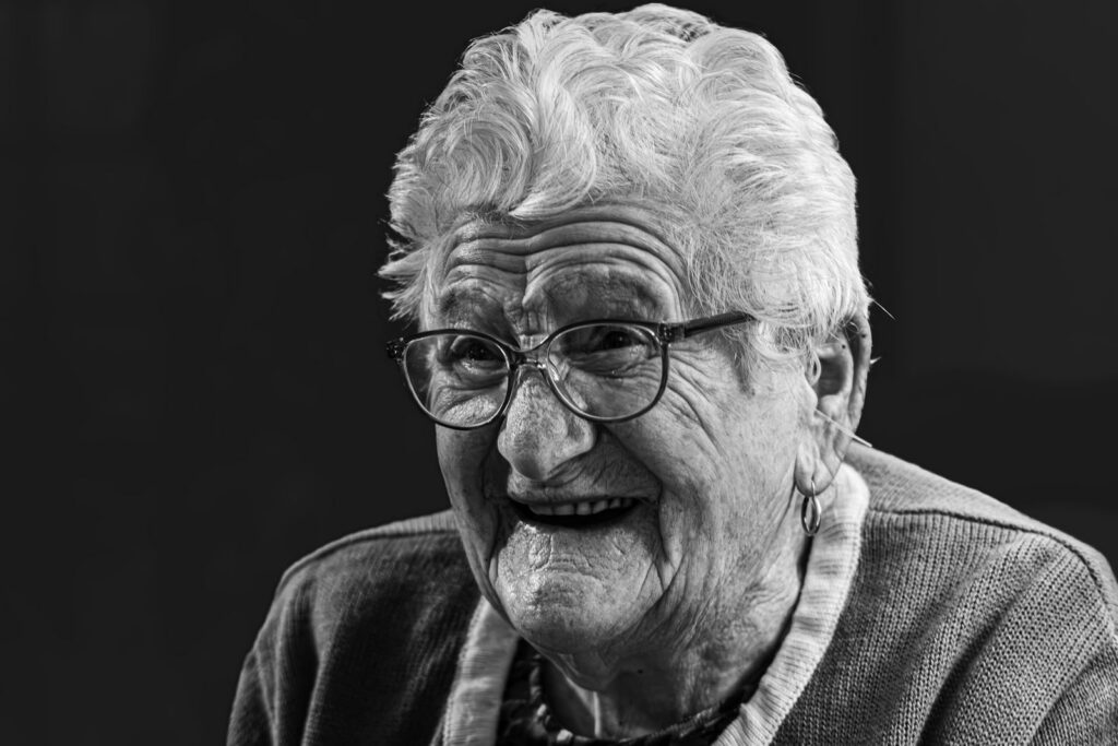 Emotive black and white portrait capturing a joyful elderly woman's smile.
