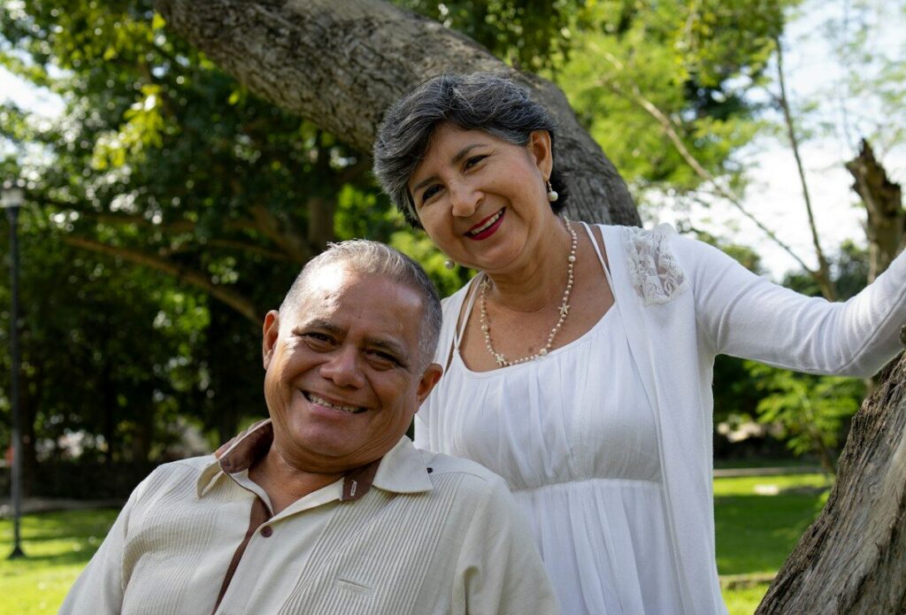 Smiling couple poses near a tree outdoors.