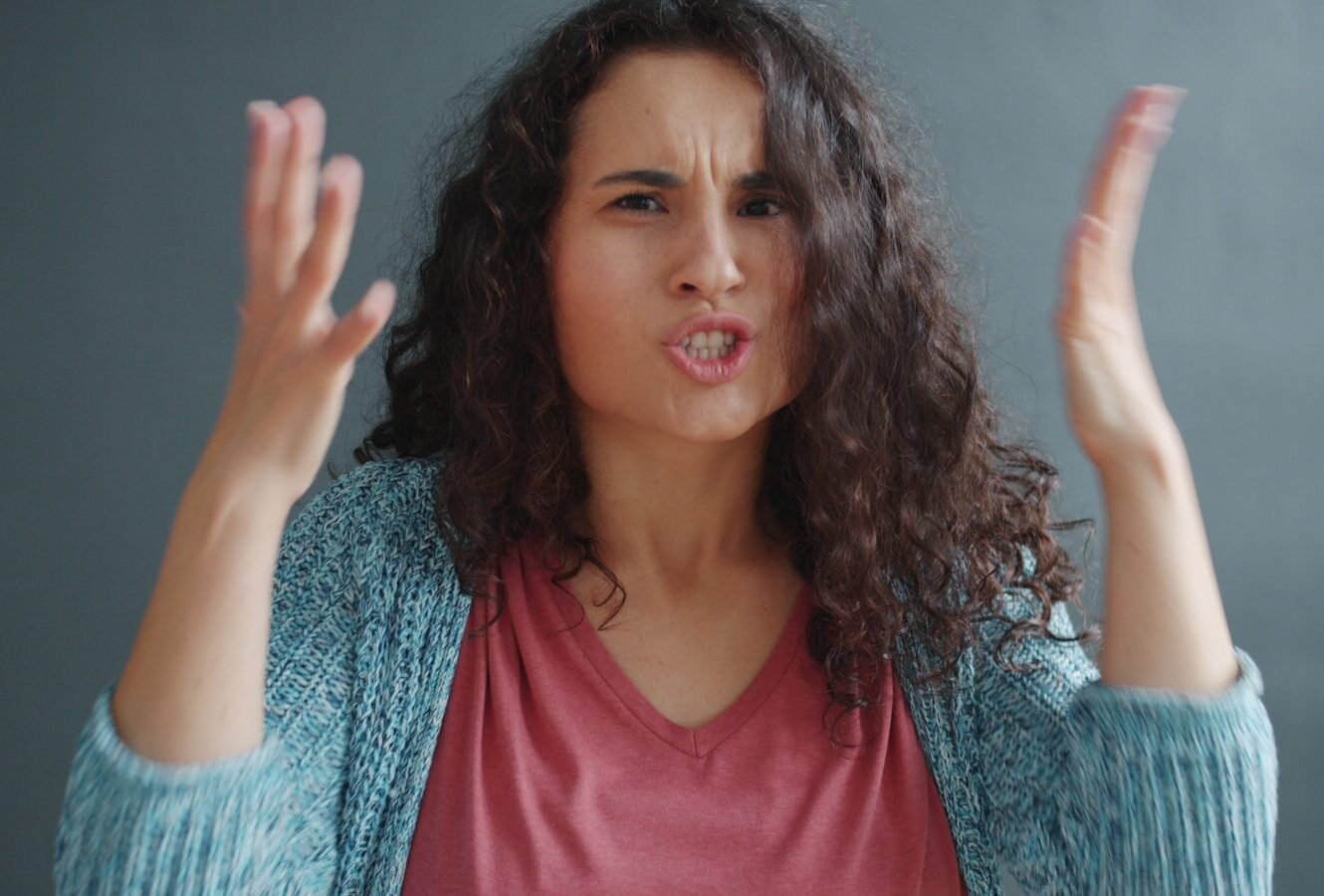 Woman with curly hair looking angry and frustrated